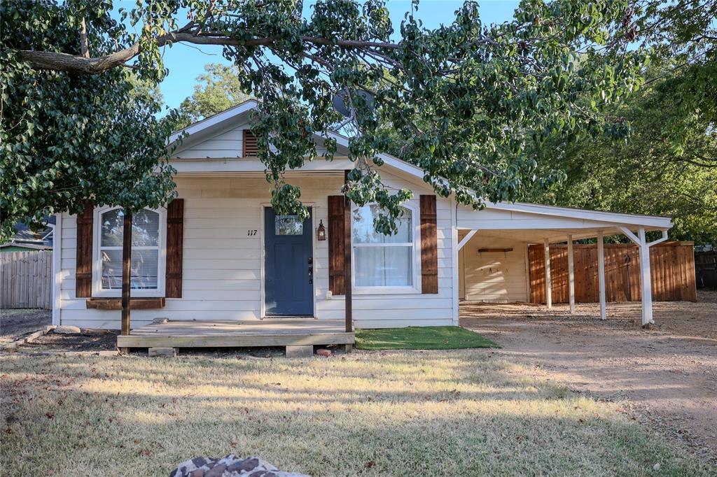 117 East Division Street Pilot Point, TX 76258 - Photo 17 of 19 White siding exterior with a blue entry door, wood shutters, and a covered front porch