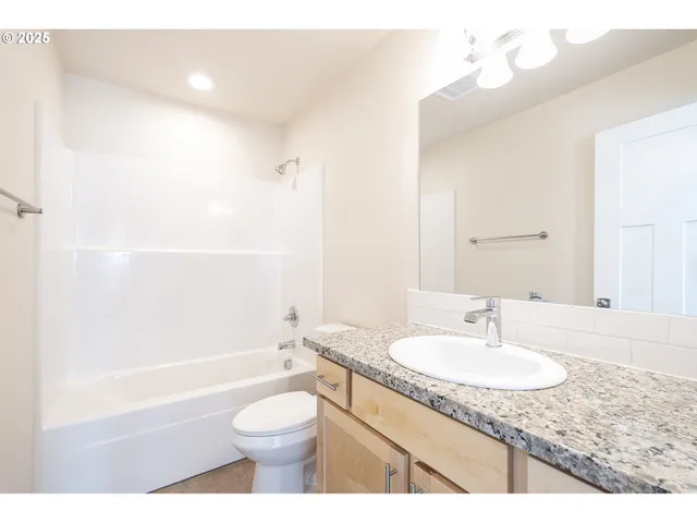 a bathroom with a granite countertop sink a toilet and shower