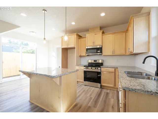 a kitchen with stainless steel appliances granite countertop a sink a stove and a refrigerator