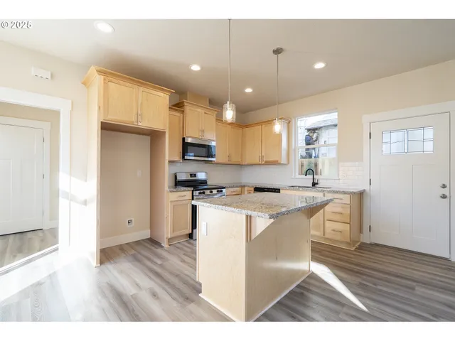 a kitchen with stainless steel appliances a stove a refrigerator a sink dishwasher and a oven with wooden floor