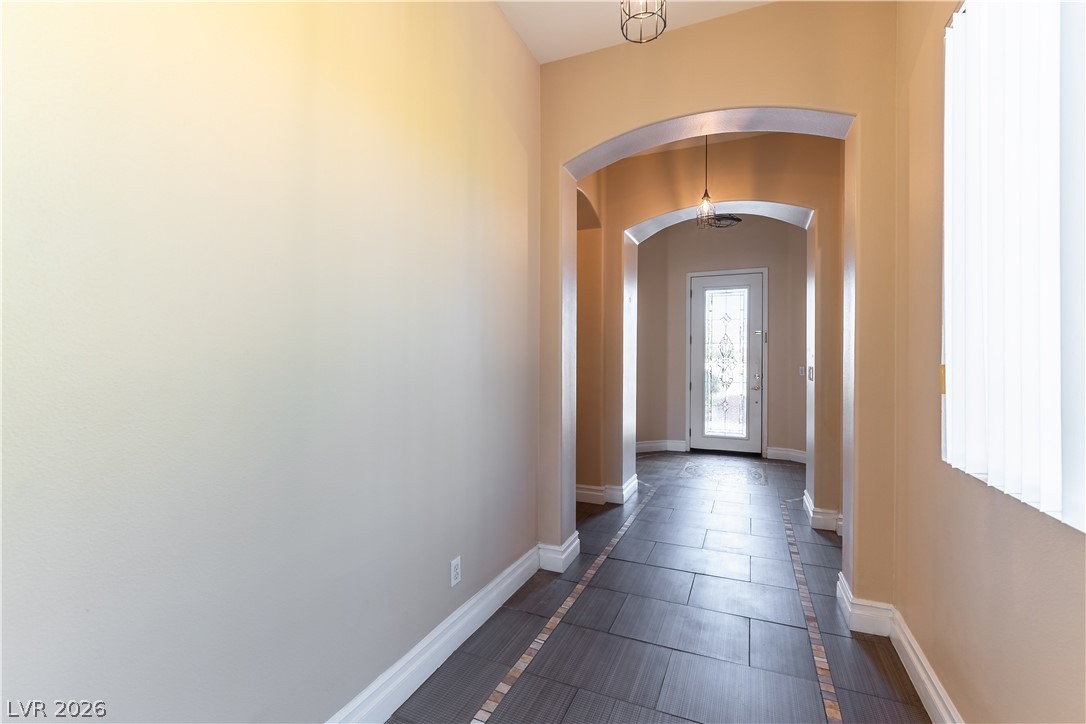 3334 Garden Shower Place Las Vegas, NV 89135 - Photo 4 of 32 Elegant arched doorways frame the view down a tiled hallway toward the entrance foyer.