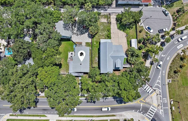 an aerial view of a house with a yard and trees all around