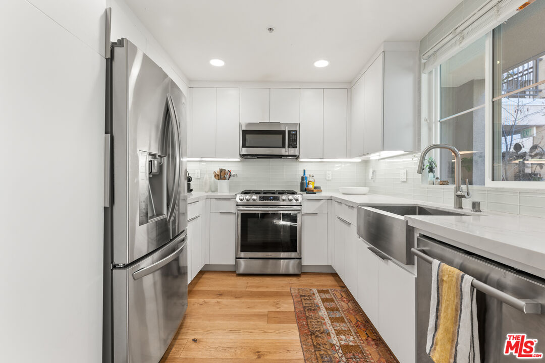 6020 South Seabluff Drive, Unit 131 Playa Vista, CA 90094 - Photo 12 of 30 a kitchen with white cabinets and stainless steel appliances