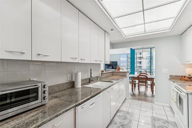 a kitchen with granite countertop a sink and white cabinets