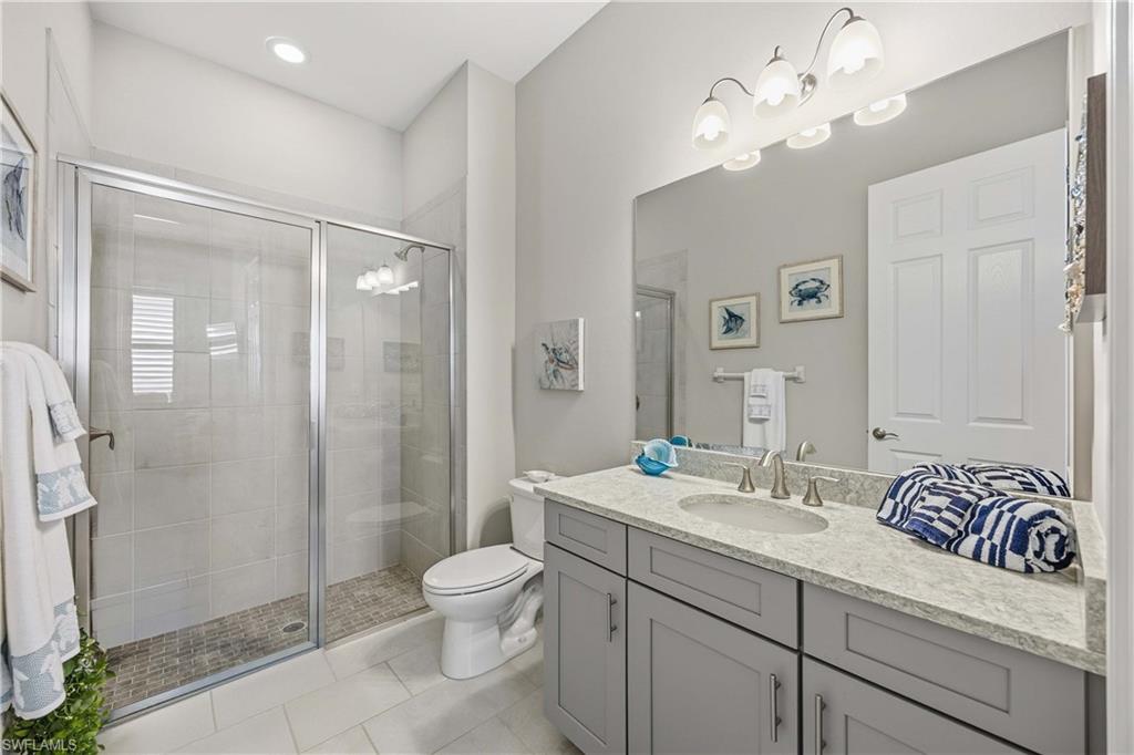 14748 Windward Lane Naples, FL 34114 - Photo 19 of 47 a bathroom with a sink a toilet a mirror and shower