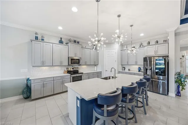 a kitchen that has a lot of cabinets a sink and chairs in it