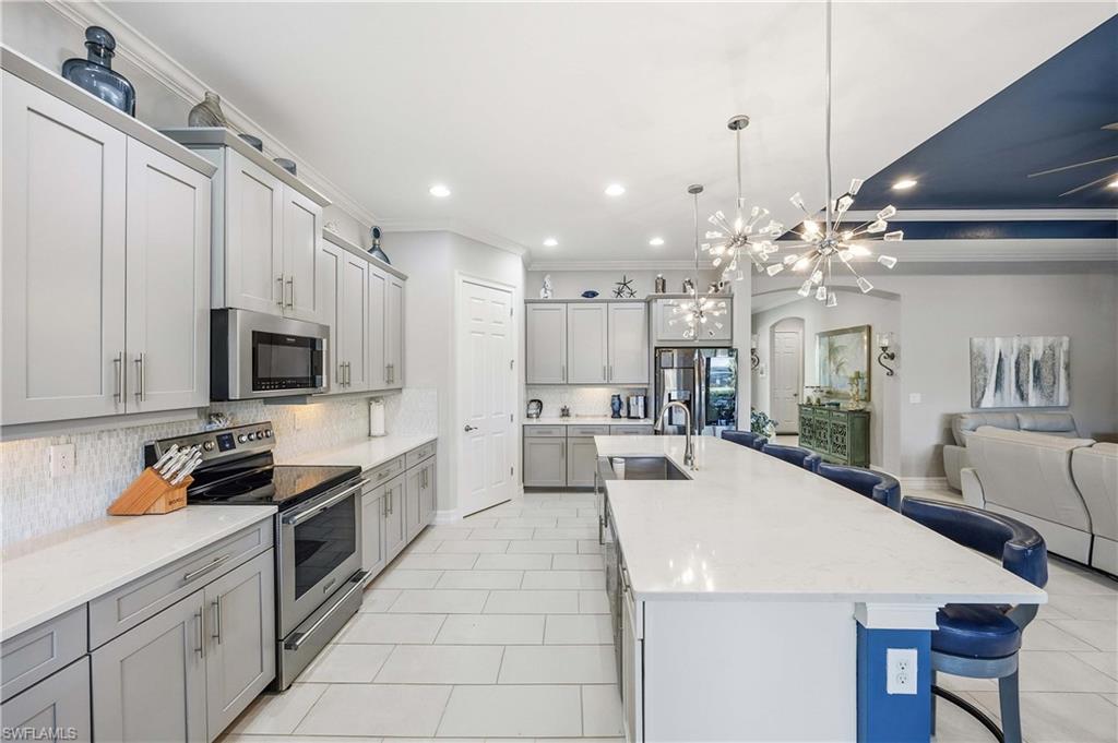 14748 Windward Lane Naples, FL 34114 - Photo 10 of 47 a kitchen with stainless steel appliances kitchen island granite countertop a sink and cabinets