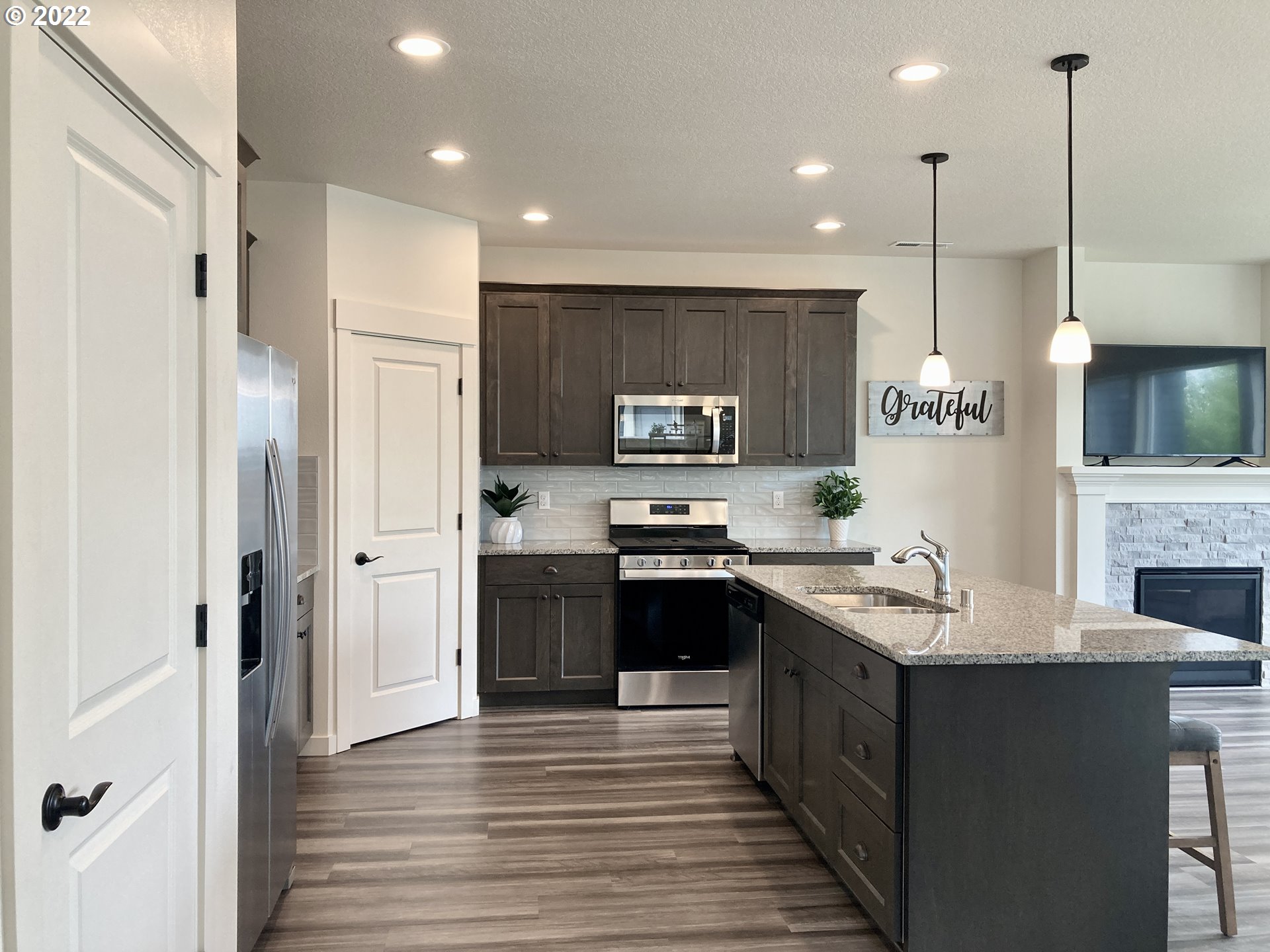 7138 South 11th Street Ridgefield, WA 98642 - Photo 5 of 14 a kitchen with stainless steel appliances granite countertop a refrigerator a stove top oven a sink dishwasher and a refrigerator with wooden floor