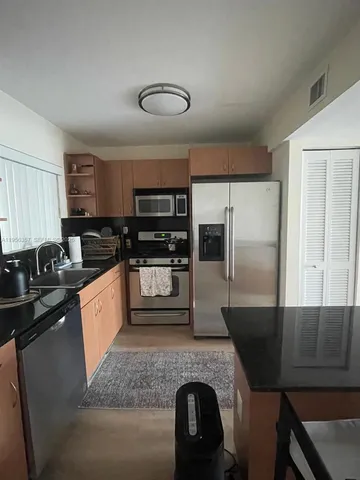 a large kitchen with granite countertop lots of counter space and stainless steel appliances
