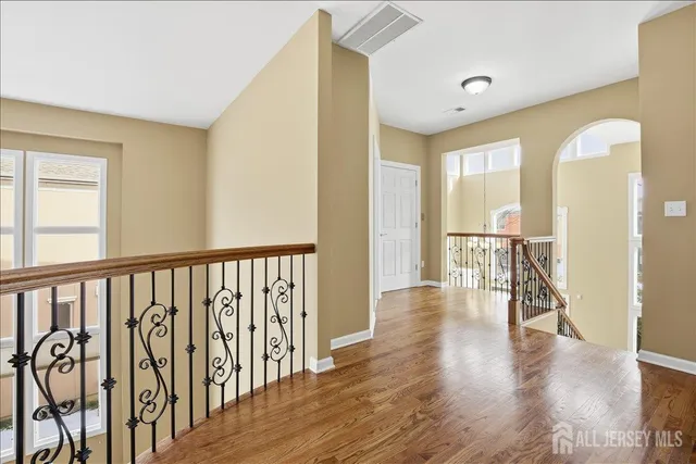 an empty room with wooden floor chandelier fan and windows