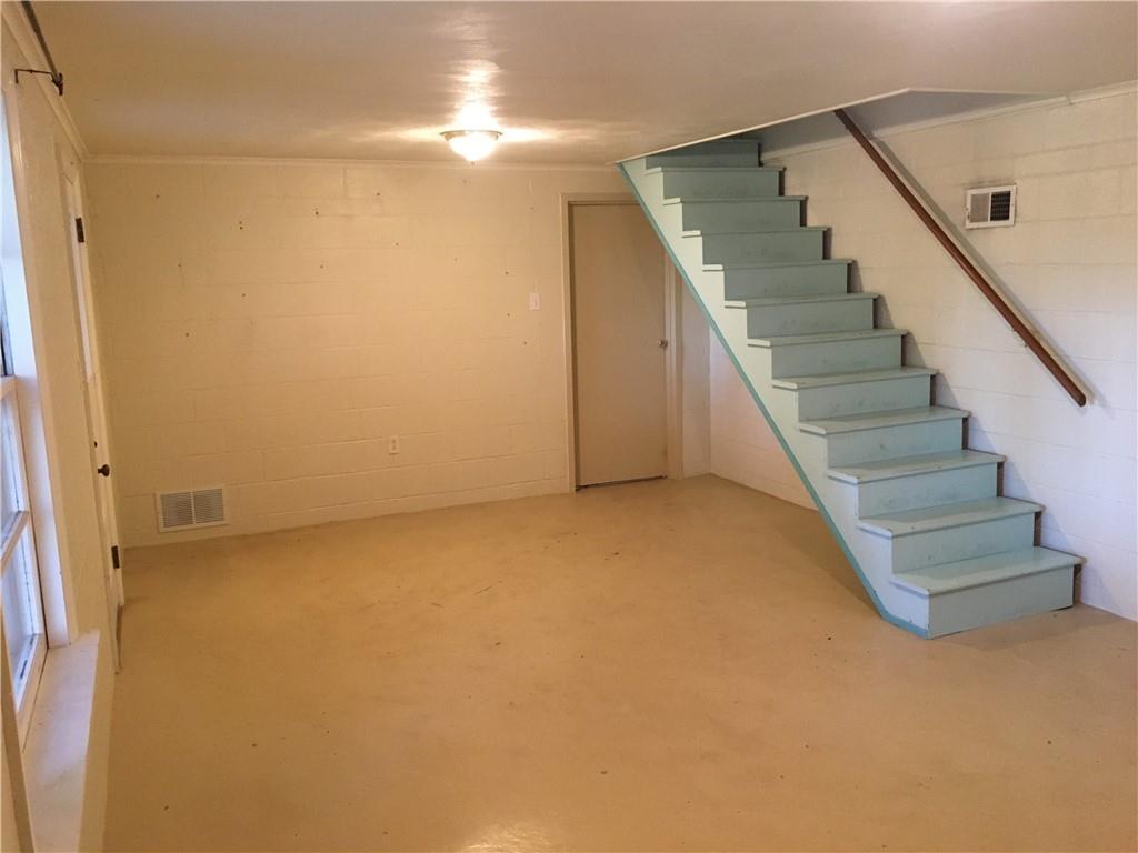 582 Weaver Mill Road Rector, PA 15677 - Photo 24 of 25 The 13 x 21 lower level future Family Room is clean, dry and useable as-is but could easily be finished off into a special getaway area. If one so chooses, this could be finished to a Den adding a sleeper sofa and an extra guest sleeping area. The back door leads to the garages. The door to the far left (see the knob) leads to the back cement patio. The stairs lead to the hallway connecting the Living Room & Kitchen. Perhaps this could even be a locked economy short-term rental guest space.