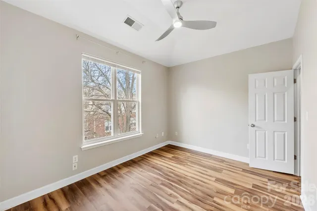 a view of empty room with wooden floor and fan