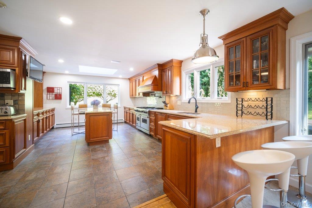 237 Mineral Springs Road Highland Mills, NY 10930 - Photo 12 of 32 Kitchen featuring a kitchen breakfast bar, tasteful backsplash, glass insert cabinets, a peninsula, and brown cabinetry