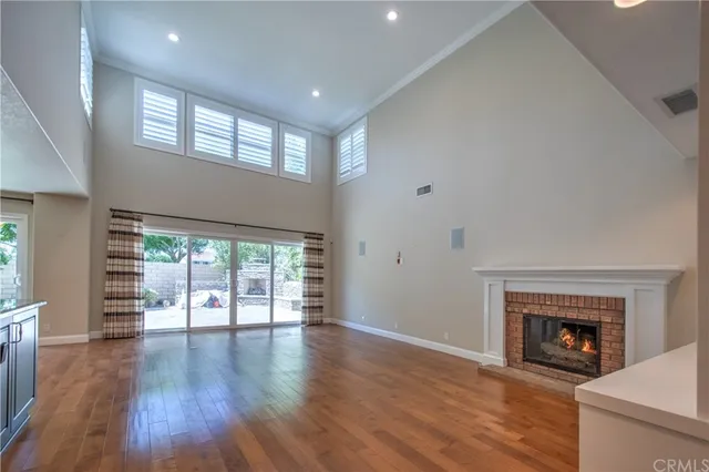 a open kitchen with stainless steel appliances granite countertop a stove top oven a large refrigerator a dining table and chairs with wooden floor