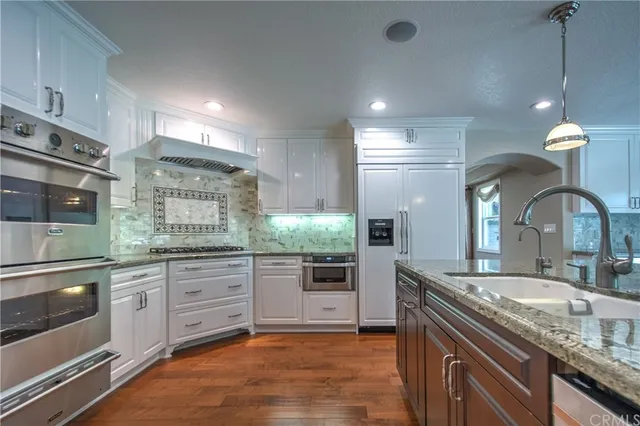 an empty room with wooden floor cabinet and windows