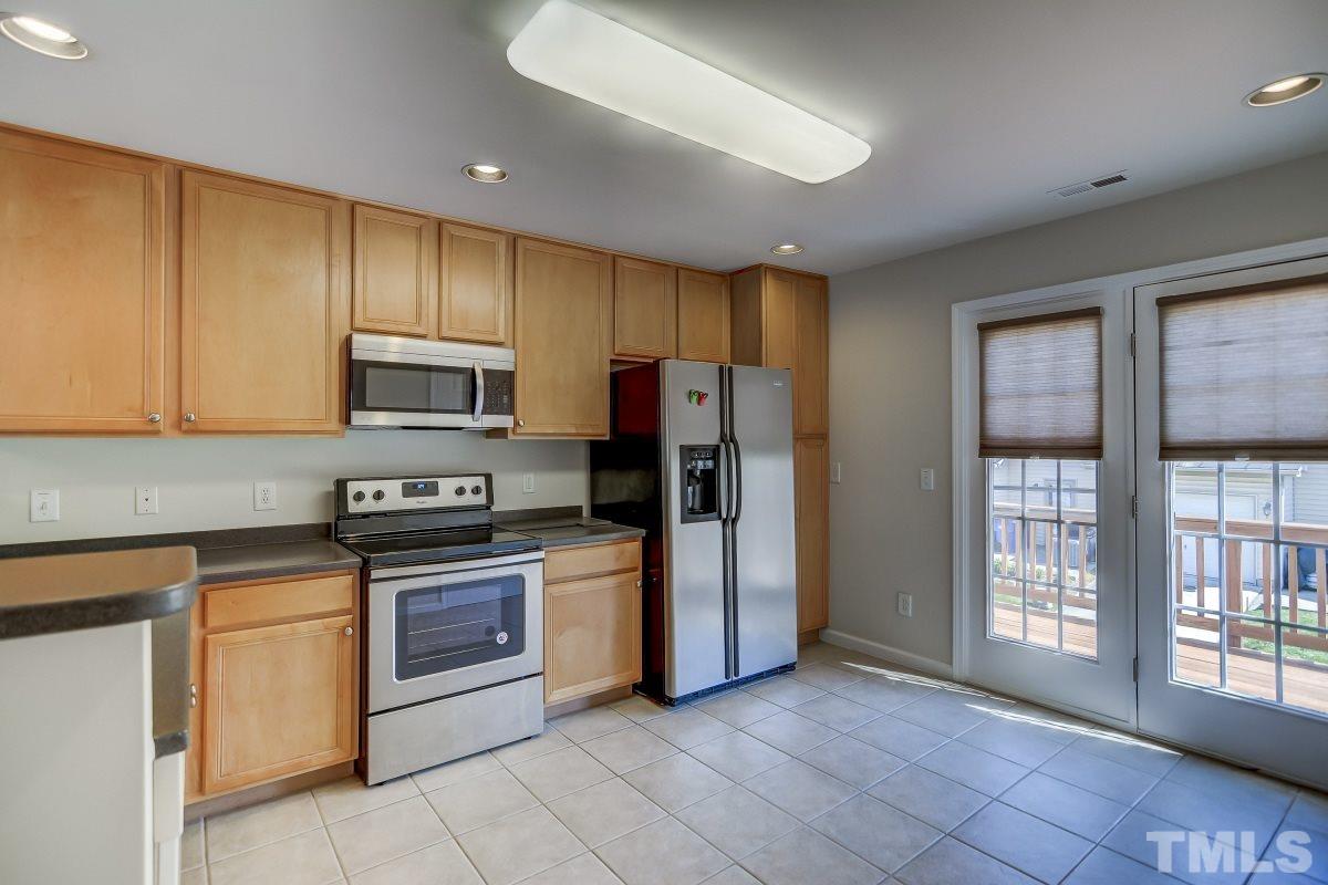 9813 Castain Drive Raleigh, NC 27617 - Photo 7 of 16 a kitchen with stainless steel appliances granite countertop a refrigerator oven a sink dishwasher and white cabinets with wooden floor