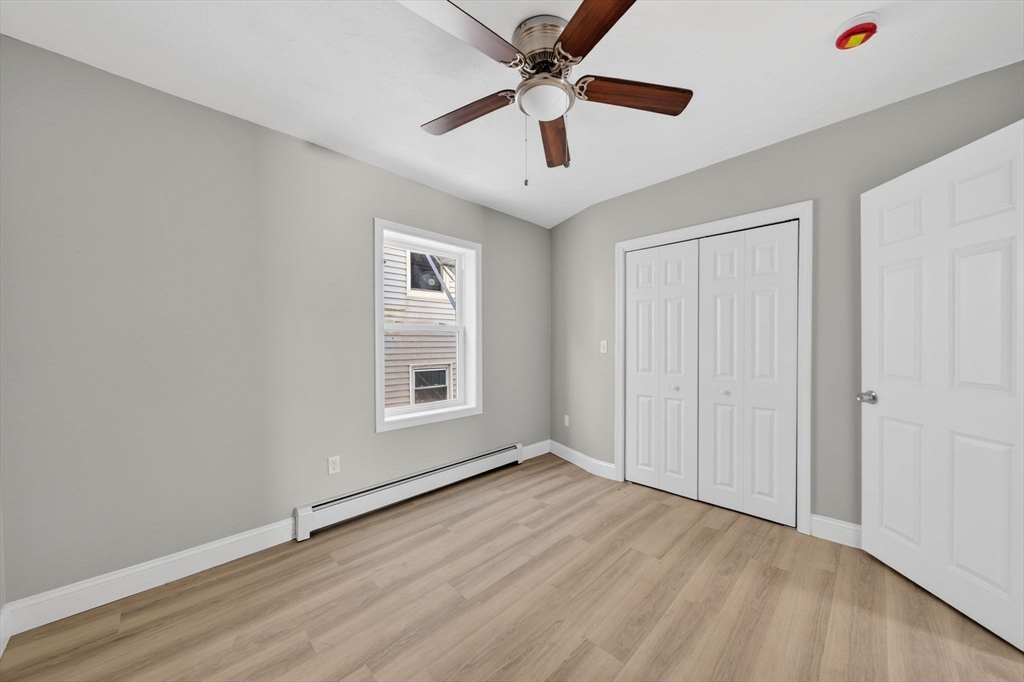 169 Grant Street Fall River, MA 02721 - Photo 19 of 42 an empty room with wooden floor ceiling fan and windows