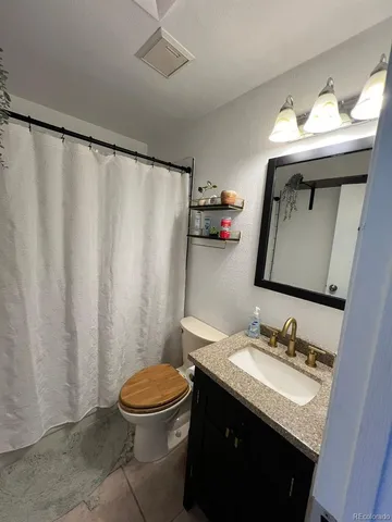 a bathroom with a granite countertop sink toilet and a mirror