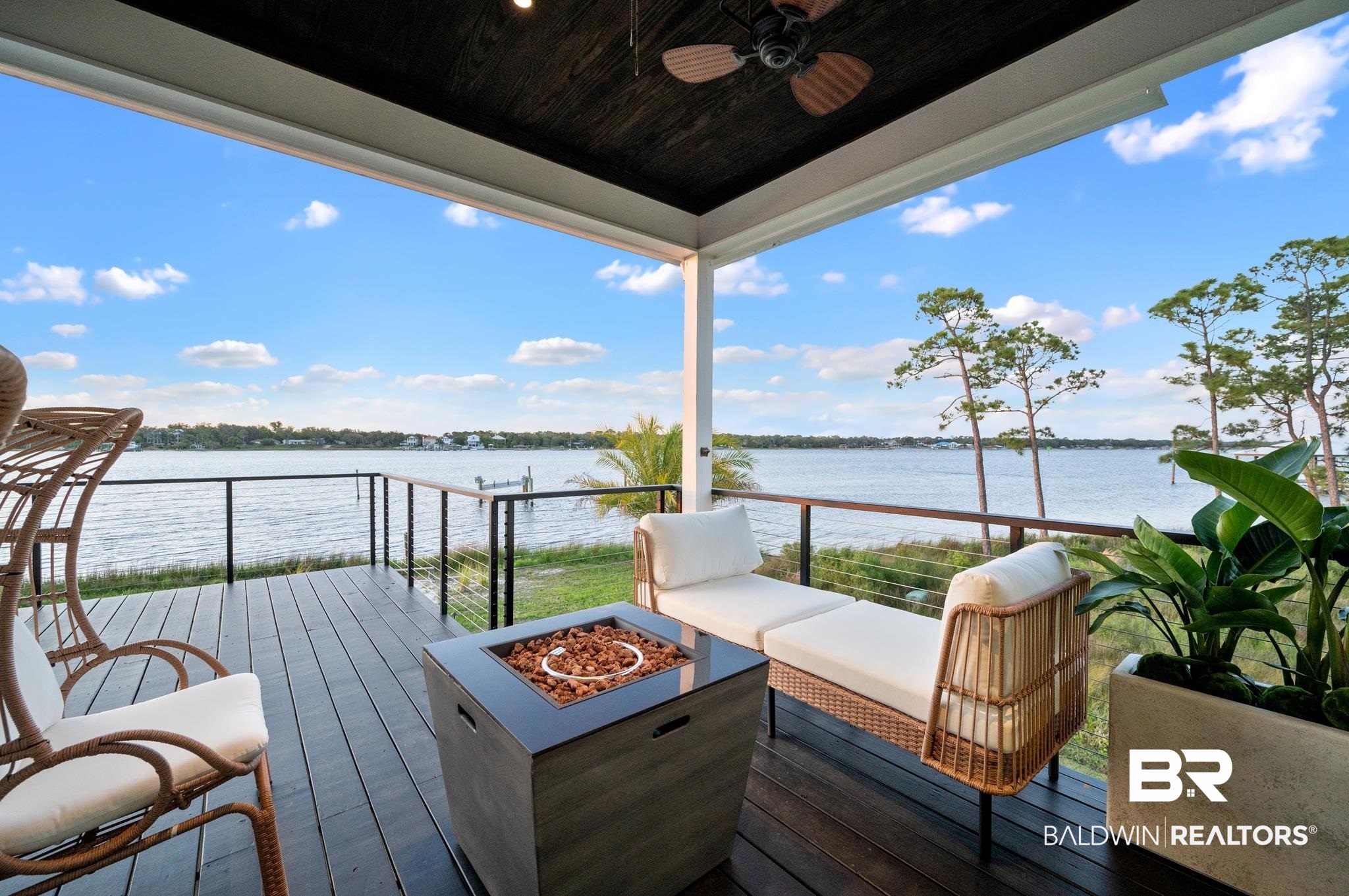 33349 River Road Orange Beach, AL 36561 - Photo 5 of 61 Covered outdoor deck with dark wood-finish flooring, featuring a built-in fire pit, black metal railings, and a ceiling fan