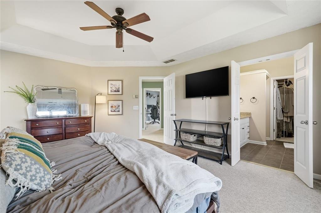 3295 Dundee Ridge Way Duluth, GA 30096 - Photo 16 of 34 a bedroom with a bed a flat screen tv and couches