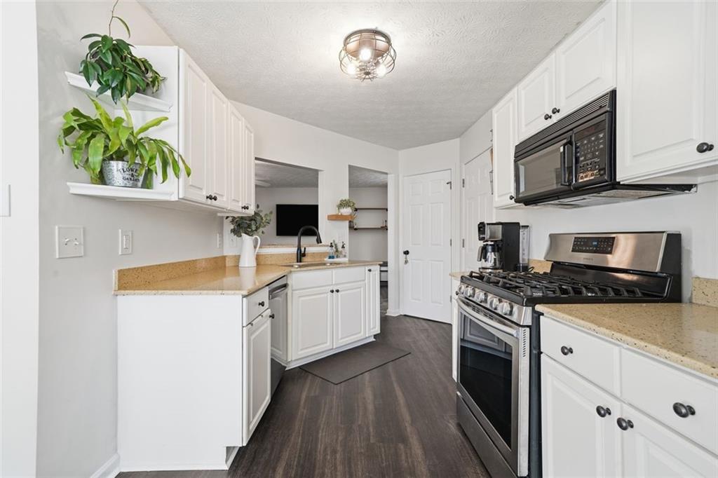 3295 Dundee Ridge Way Duluth, GA 30096 - Photo 10 of 34 a kitchen with stainless steel appliances a stove microwave and sink