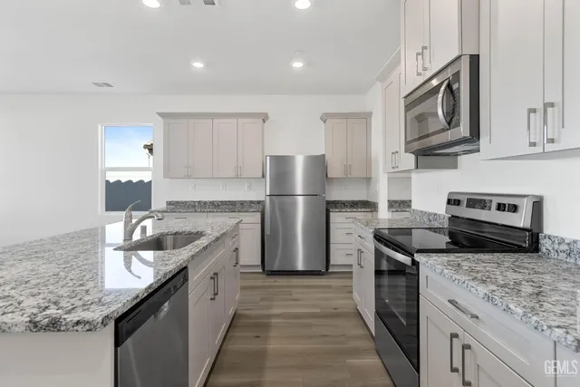a kitchen with stainless steel appliances granite countertop a sink stove and refrigerator