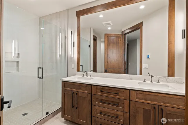 a bathroom with a double vanity sink mirror and shower
