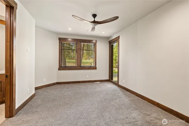 an empty room with ceiling fan and windows