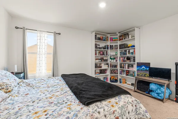 a bedroom with a bed a book shelf and a window