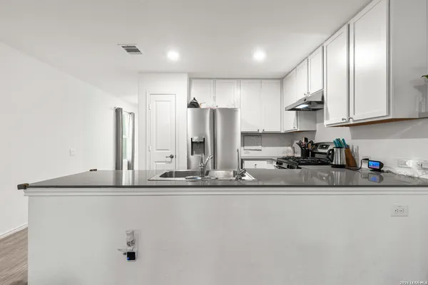a kitchen with stainless steel appliances granite countertop a sink refrigerator and cabinets