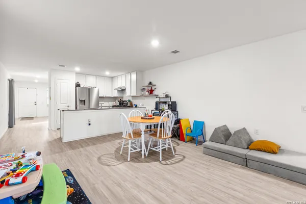 a living room with furniture and a dining table with wooden floor