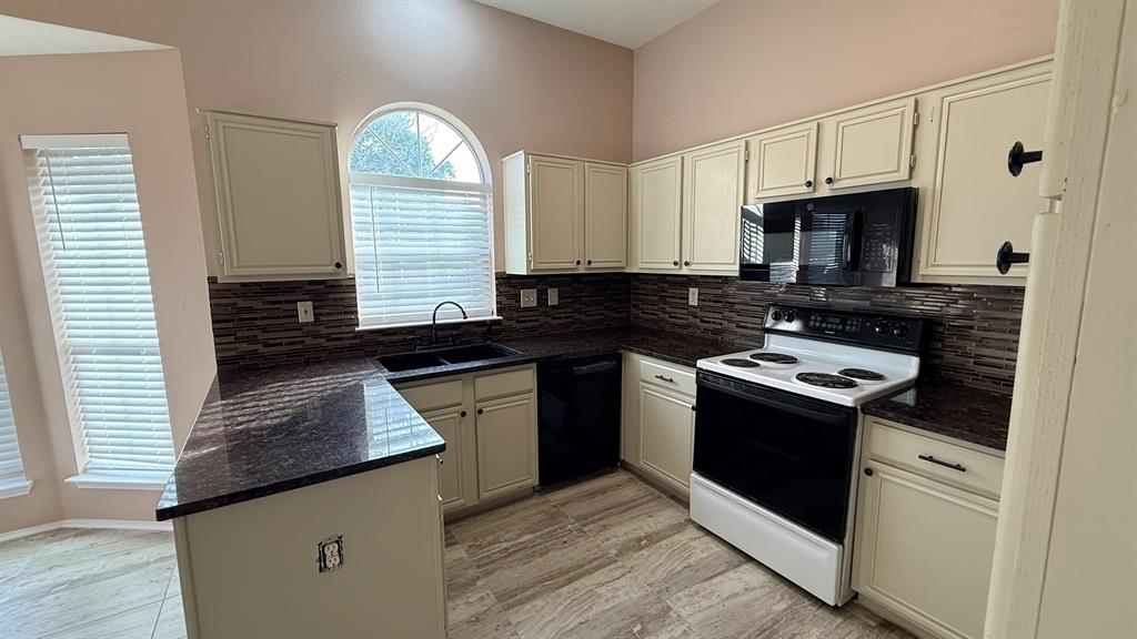 12259 Rim Rock Road Dallas, TX 75253 - Photo 6 of 17 Kitchen with black appliances, dark stone countertops, a peninsula, and backsplash