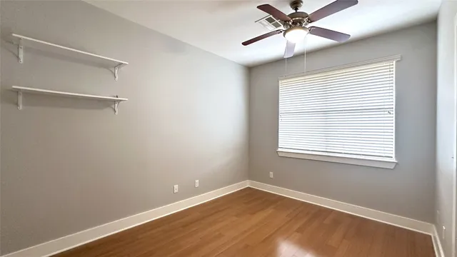 a view of an empty room with a window and a ceiling fan