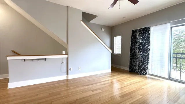 a view of an empty room with wooden floor and stairs