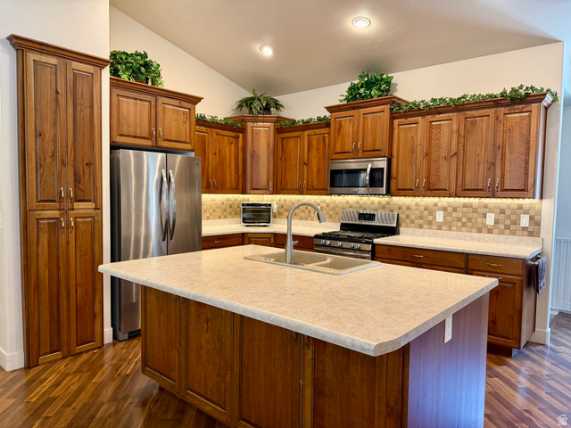1204 South 1150th Street West Payson, UT 84651 - Photo 5 of 26 Kitchen featuring wood-finish cabinetry, stainless steel appliances, a tiled backsplash, a central island with an undermount sink, and wood-finish flooring