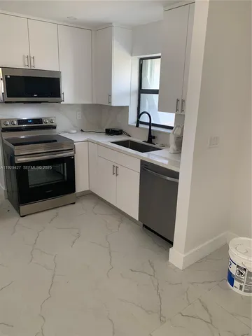 a kitchen with granite countertop a stove a sink and a microwave