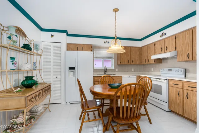 a view of kitchen with stainless steel appliances granite countertop dining table chairs sink and cabinets