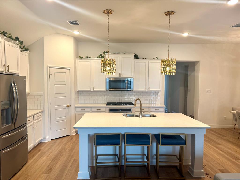7024 Tree Stand Point Little Elm, TX 76227 - Photo 7 of 30 a kitchen with a table chairs refrigerator and microwave