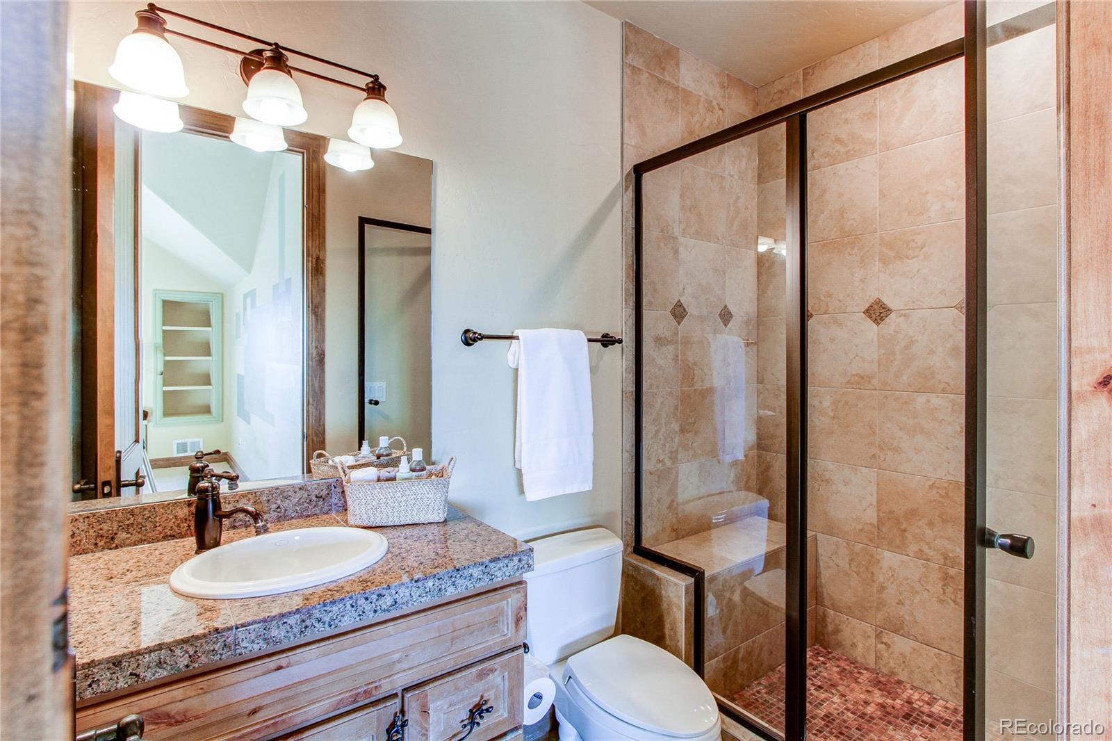5764 Amber Ridge Drive Castle Pines, CO 80108 - Photo 30 of 50 a bathroom with a granite countertop sink toilet a mirror and shower