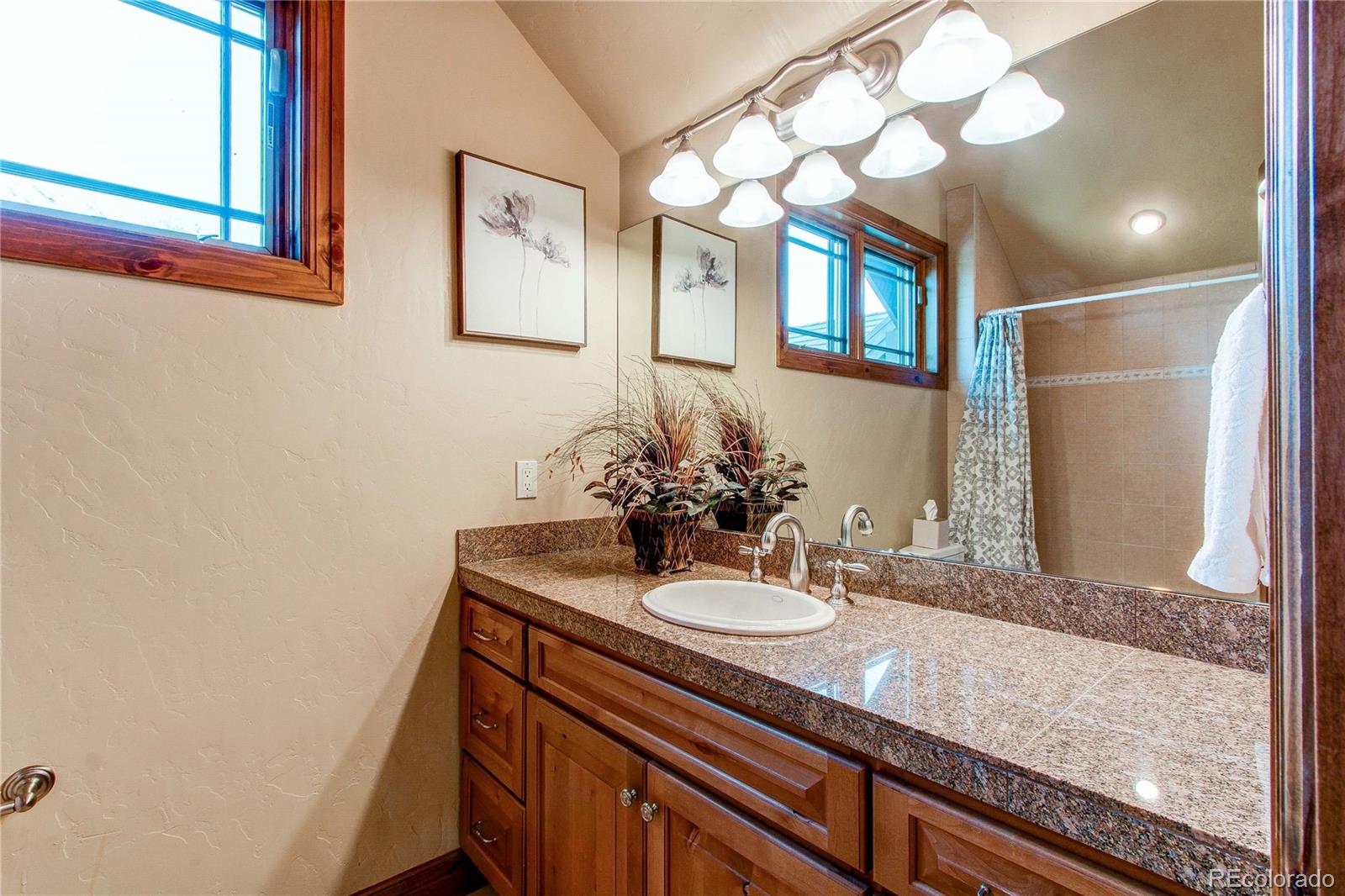 5764 Amber Ridge Drive Castle Pines, CO 80108 - Photo 34 of 50 a bathroom with a granite countertop sink a large mirror and a shower