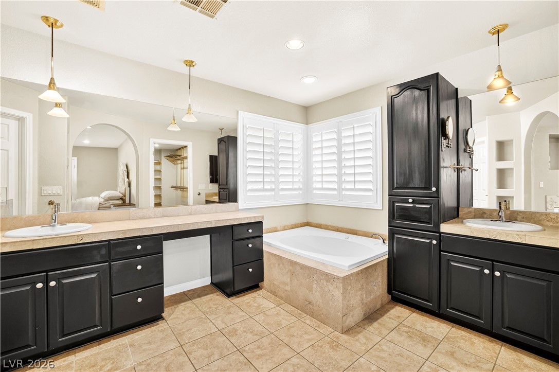 1135 Calico Ridge Drive Henderson, NV 89011 - Photo 33 of 86 An inviting primary bath offers a spacious soaking tub, dual vanities, and a walk-in closet for ultimate convenience.