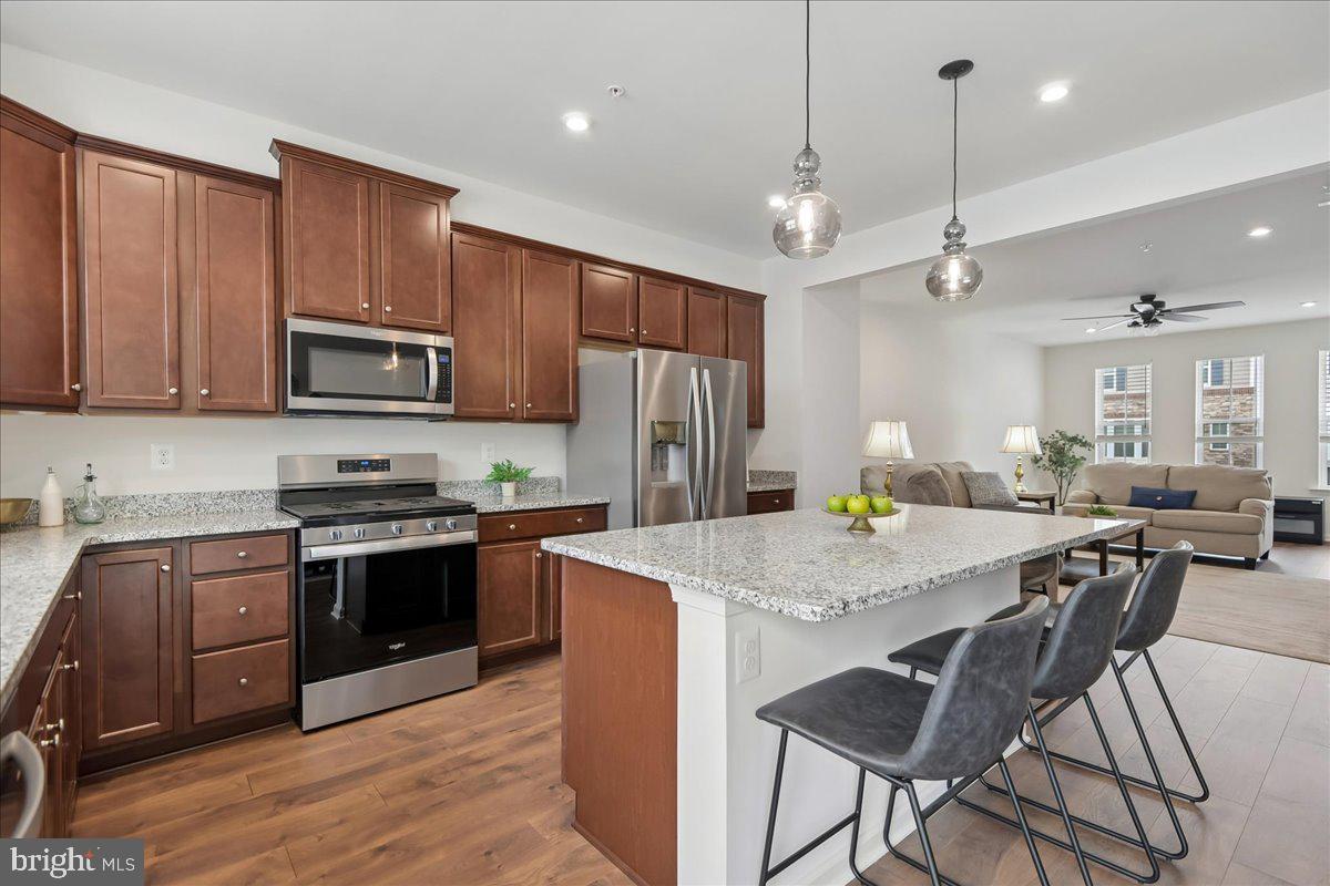 a kitchen with stainless steel appliances granite countertop a stove top oven a refrigerator a sink and chairs