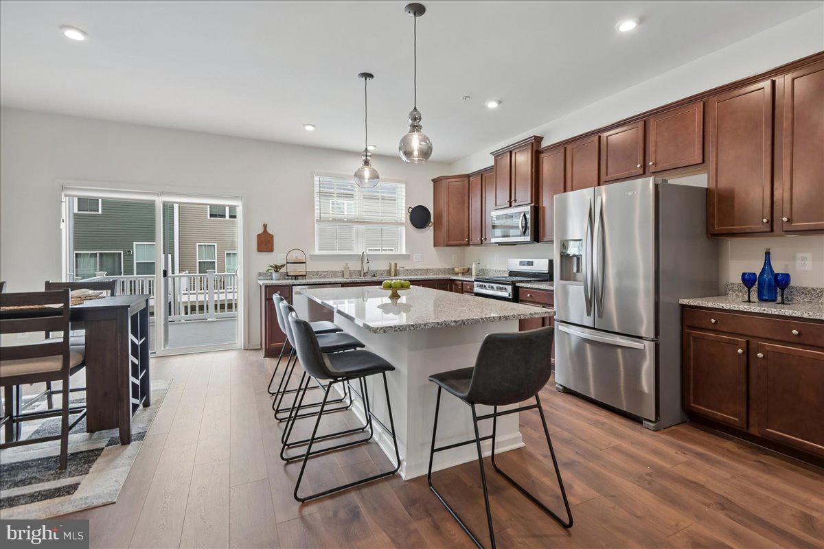 1813 Iris Lane Hanover, MD 21076 - Photo 5 of 20 a kitchen with stainless steel appliances a refrigerator a stove a sink a dining table and chairs with wooden floor