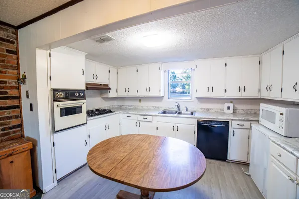 a kitchen with stainless steel appliances granite countertop a stove a sink dishwasher and a refrigerator with wooden floor