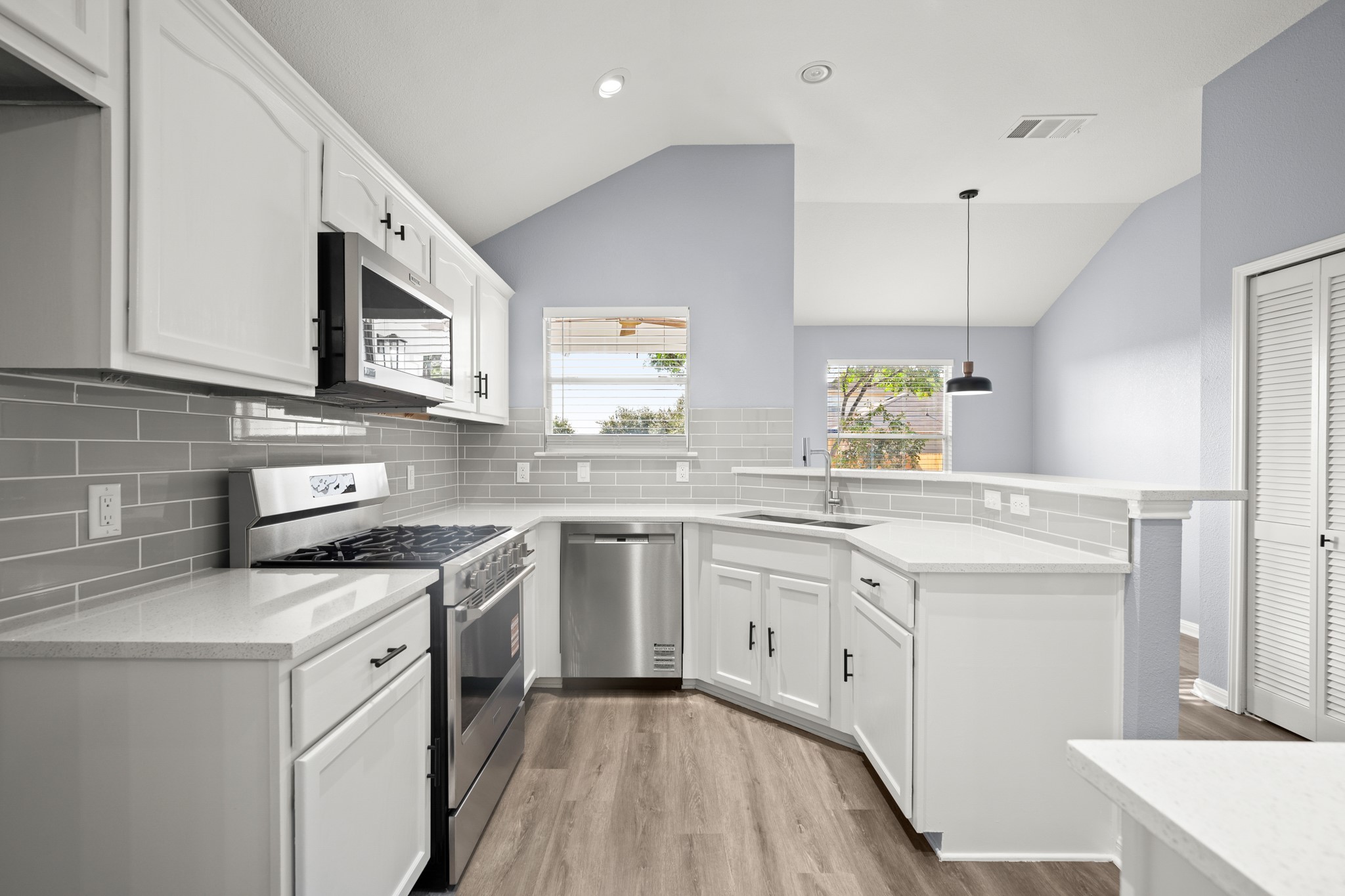 a kitchen with granite countertop a sink stainless steel appliances and white cabinets