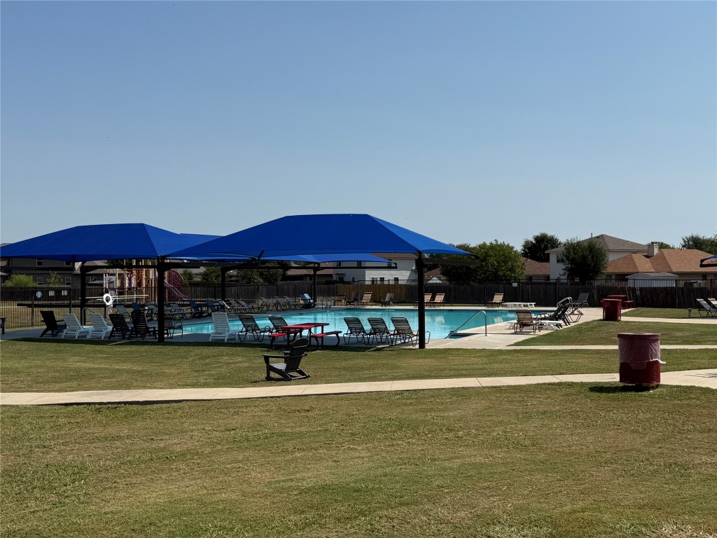 14303 Cummins Way Manor, TX 78653 - Photo 23 of 25 a view of swimming pool with lawn chairs under an umbrella