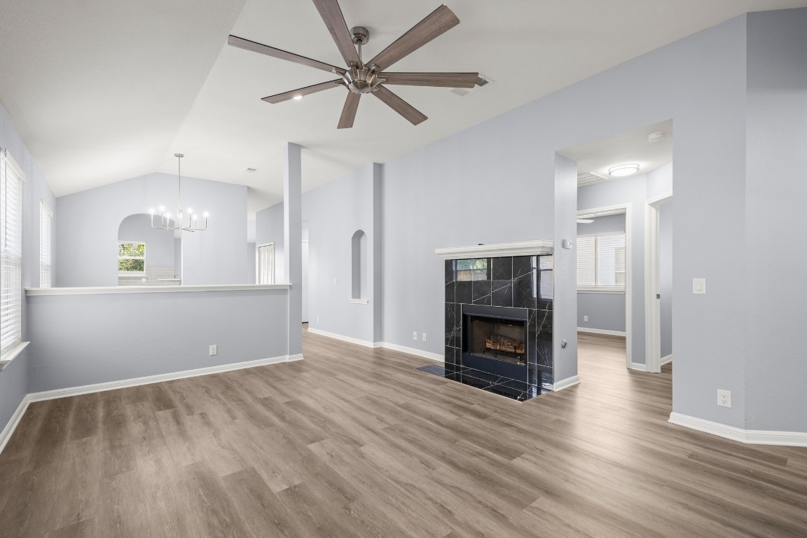 14303 Cummins Way Manor, TX 78653 - Photo 4 of 25 an empty room with wooden floor a ceiling fan and a kitchen