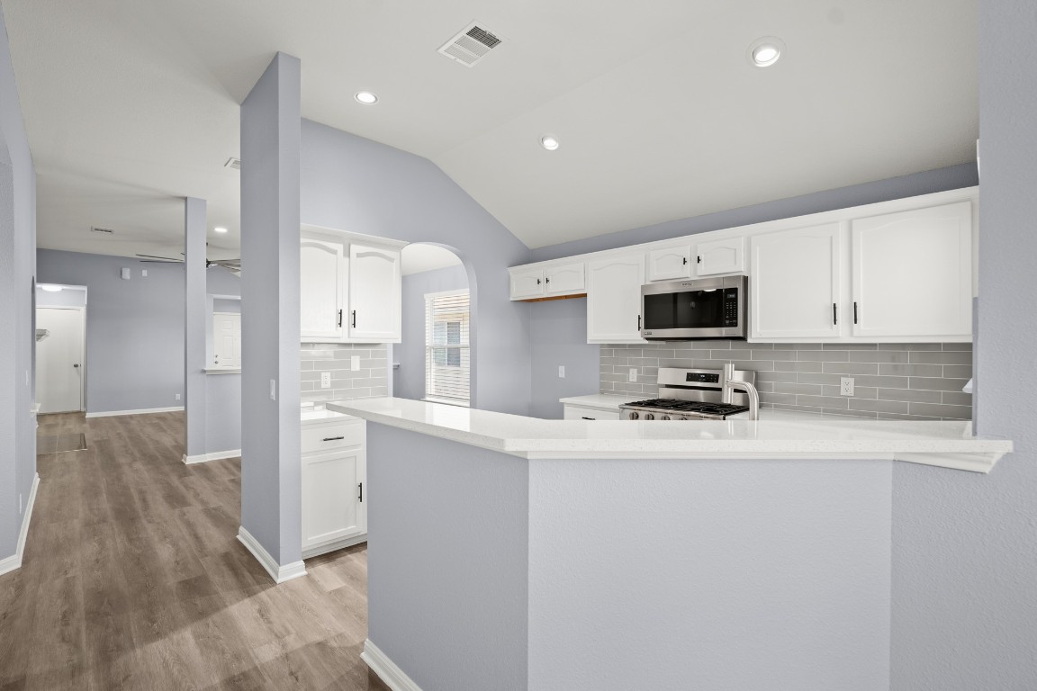 14303 Cummins Way Manor, TX 78653 - Photo 10 of 25 a kitchen with stainless steel appliances a stove top oven a sink a refrigerator white cabinets and wooden floor
