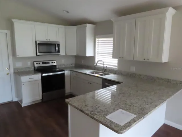 a kitchen with a sink dishwasher a refrigerator and white cabinets