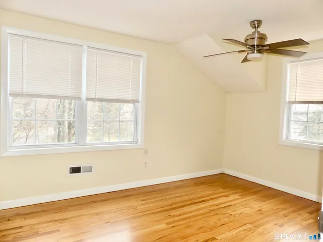a view of an empty room with a window and wooden floor